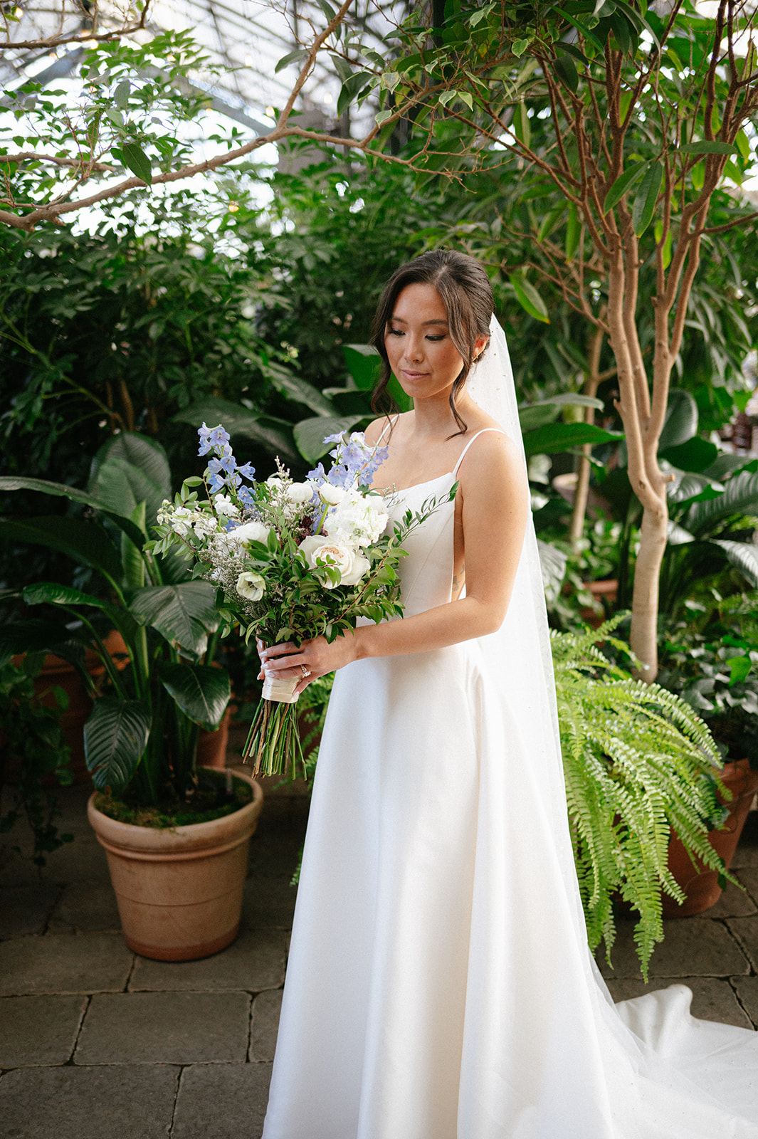 The bride posing in front of the foliage in the greenhouse at Planterra Conservatory in Michigan.