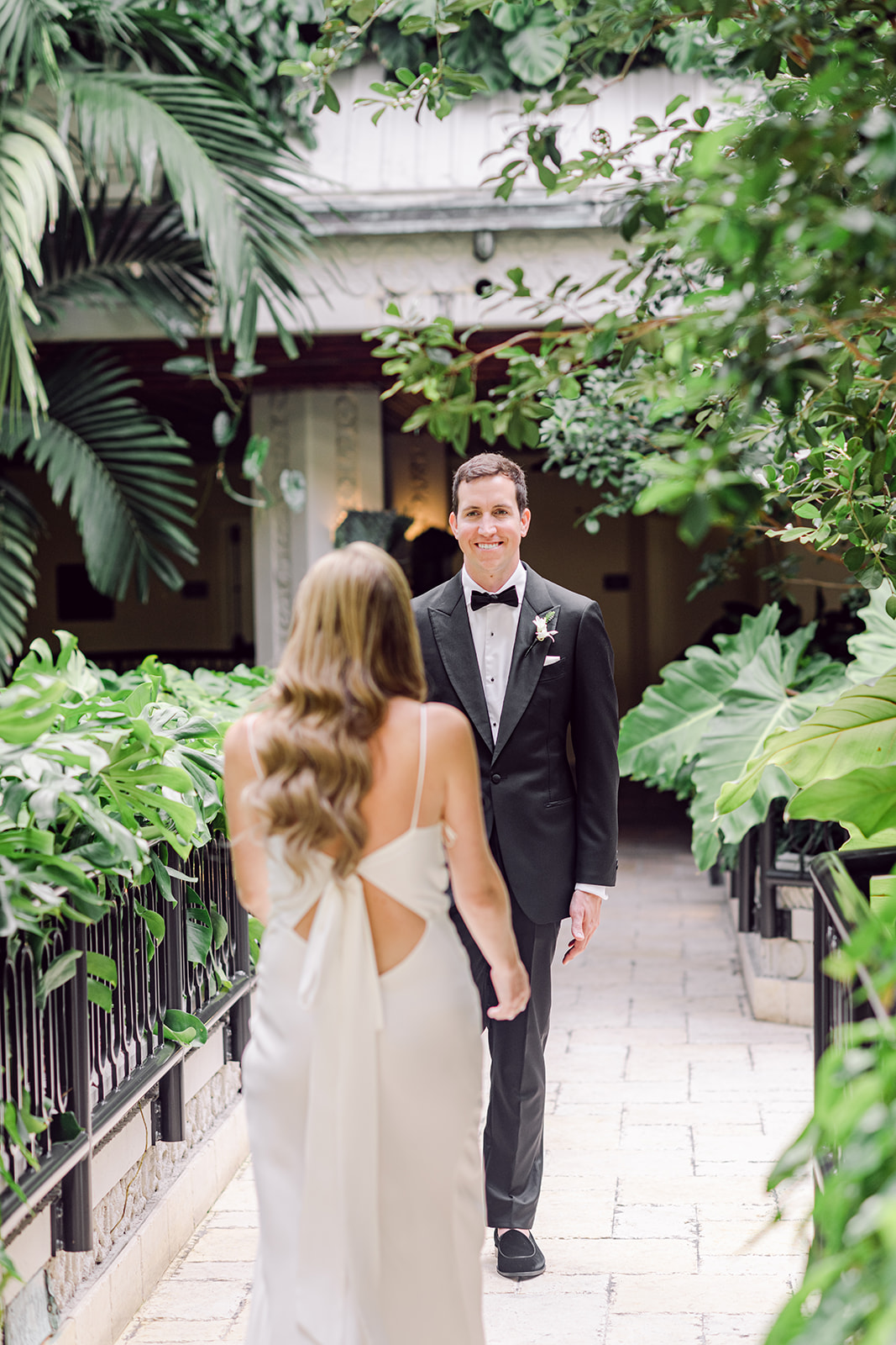 Groom sees bride for the first time during first look at Mayfair House Hotel & Garden in Miami on wedding day.