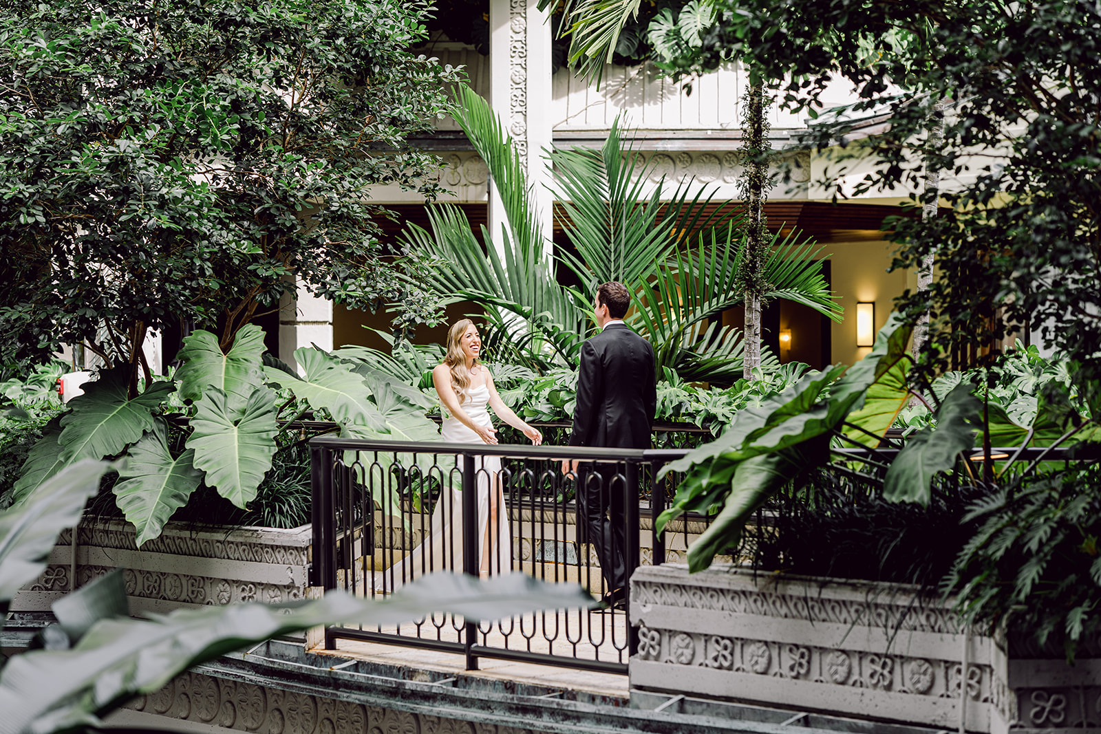 Bride reaches out to groom during first look at Mayfair House Hotel & Garden in Miami on wedding day.