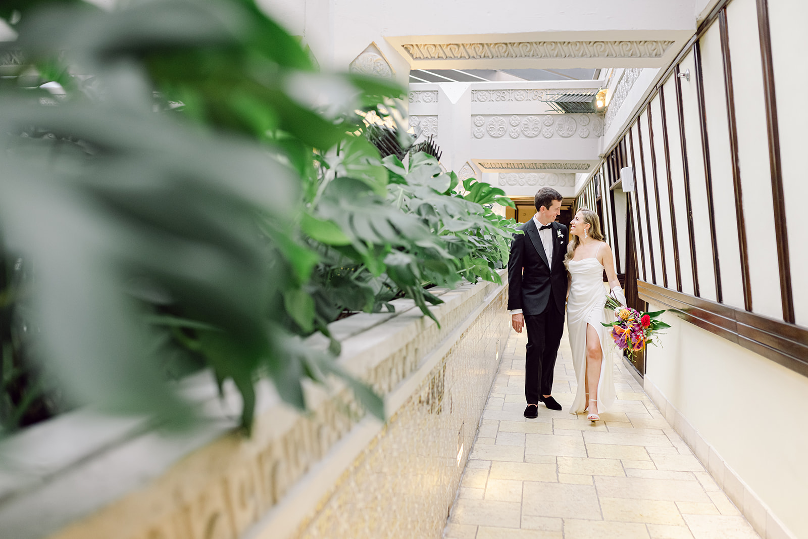 Bride & groom walking hand in hand down hallway at Mayfair House Hotel & Garden in Miami on wedding day.