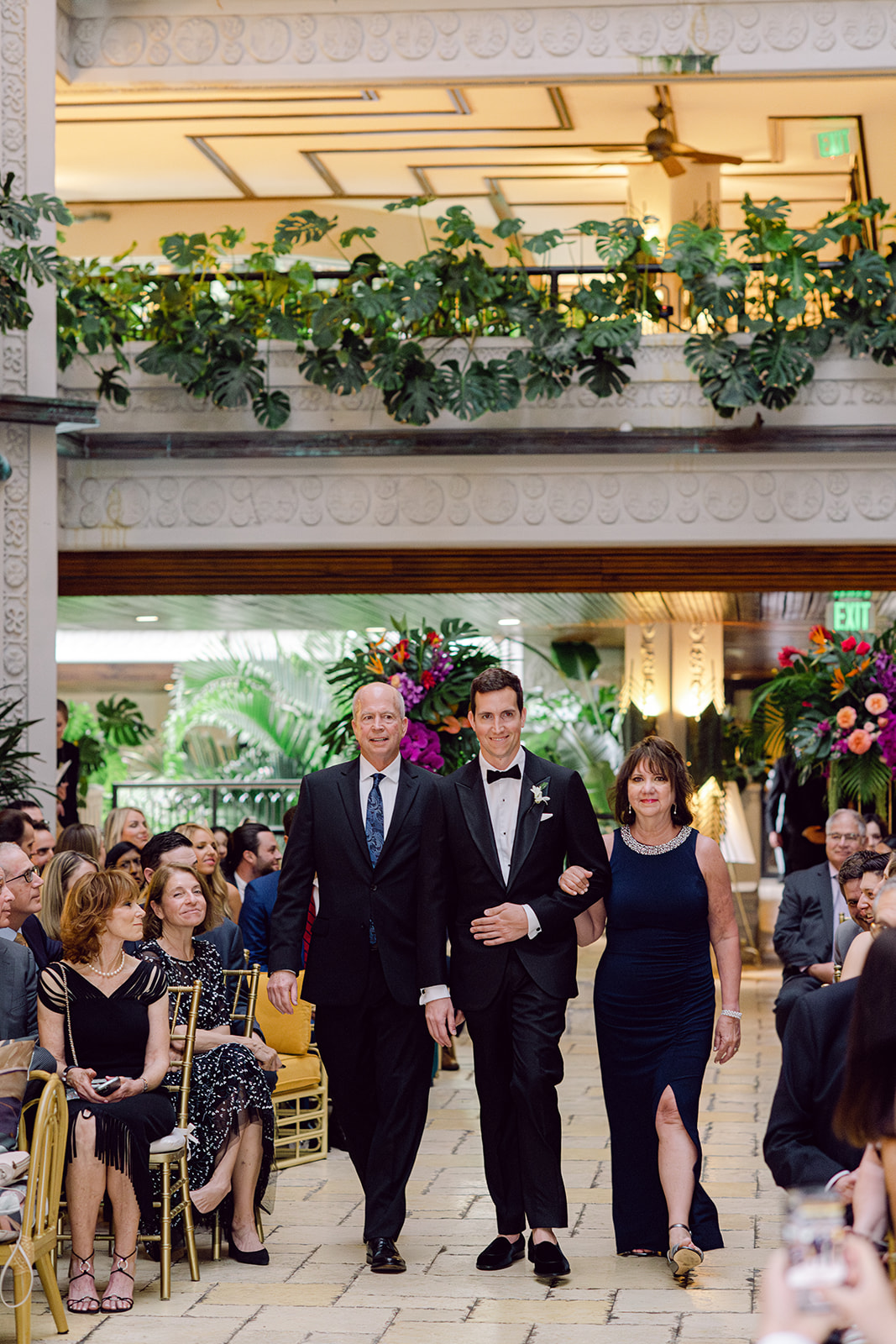 Groom walks down aisle with parents during ceremony at Mayfair House Hotel & Garden in Miami on wedding day.