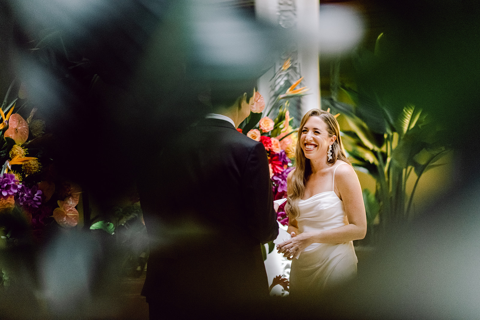 Bride smiles at groom reading vows during ceremony at Mayfair House Hotel & Garden in Miami on wedding day.