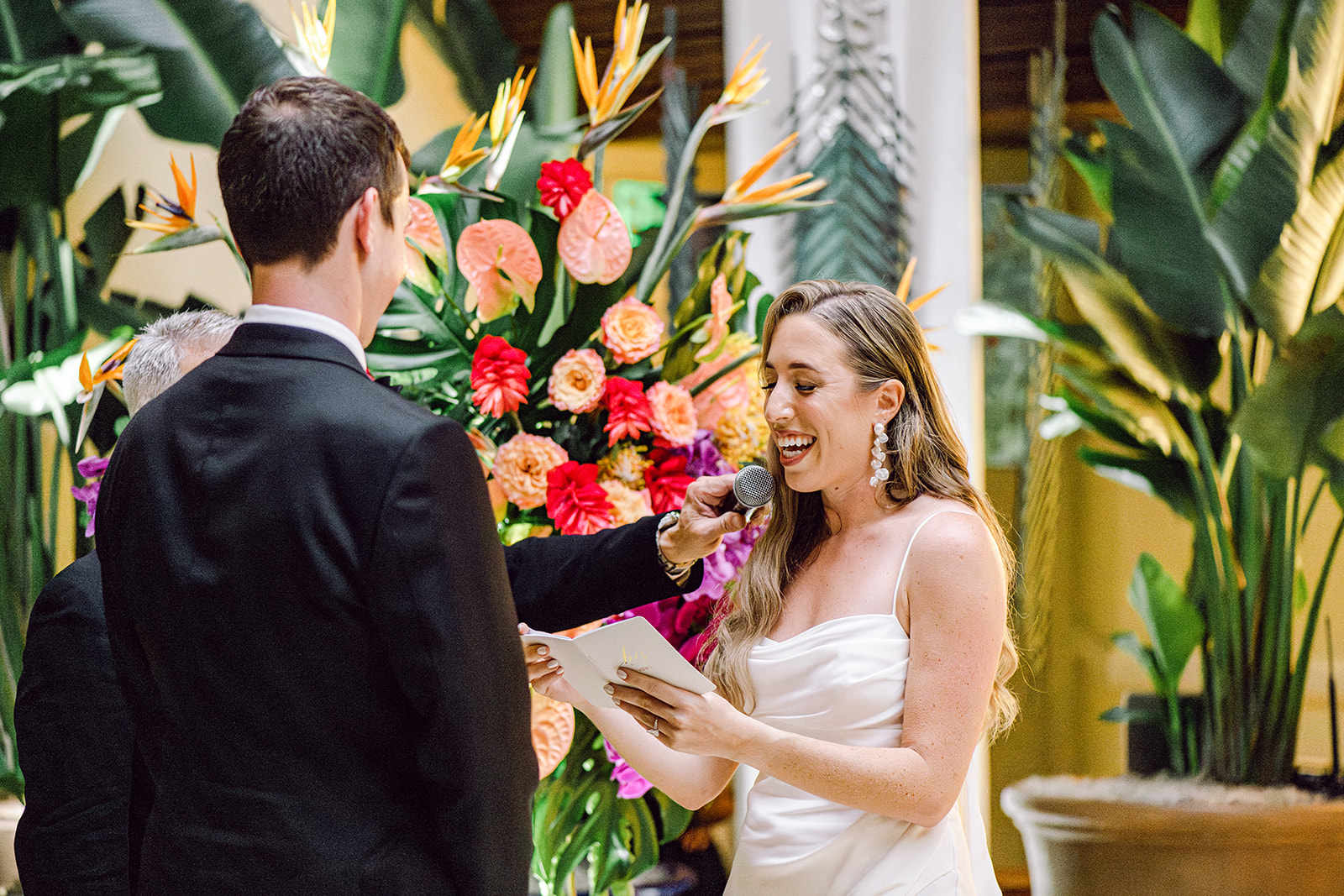 Bride smiling and reading vows to groom at during ceremony at Mayfair House Hotel & Garden in Miami on wedding day.