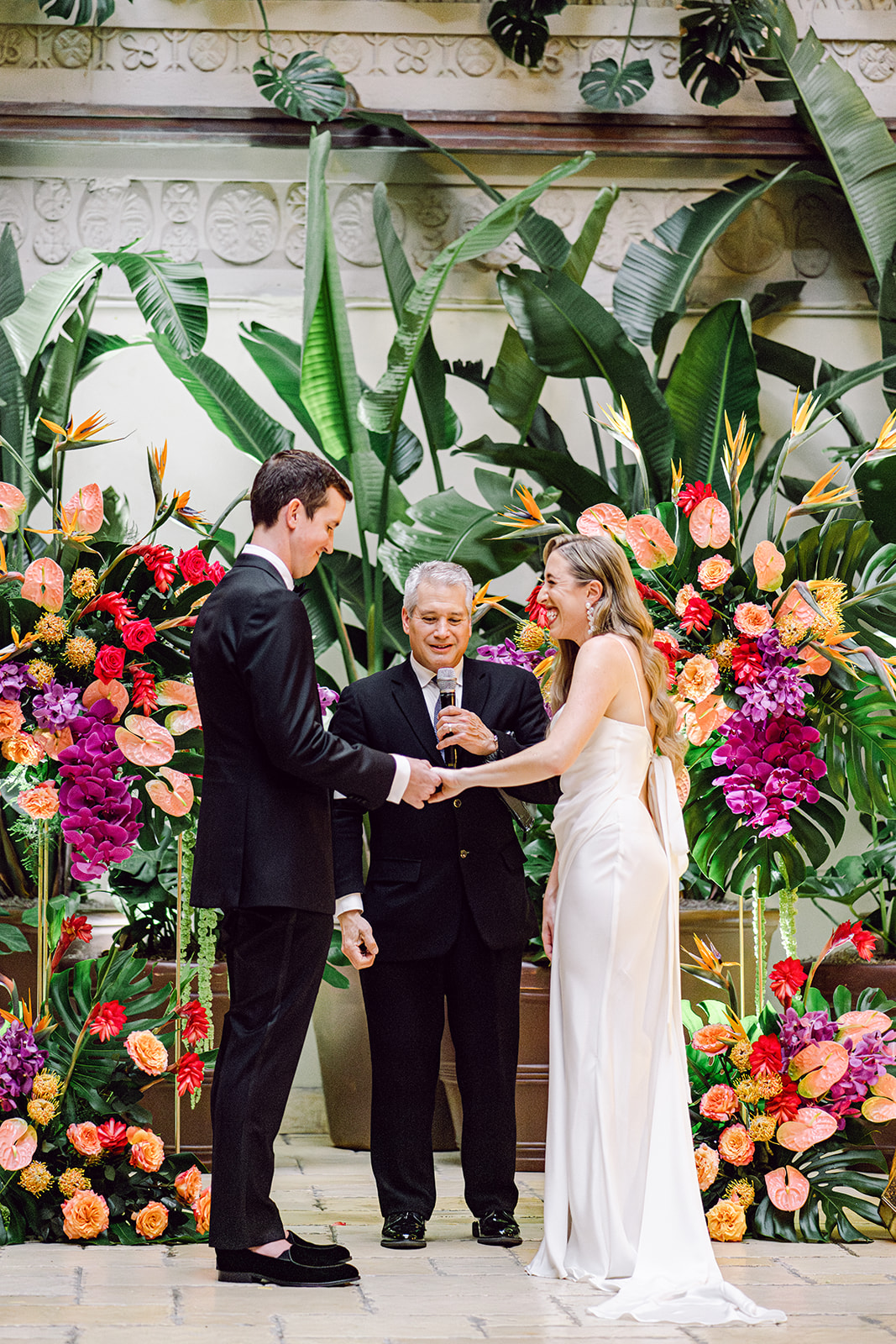Bride places wedding ring on finger of groom during ceremony at Mayfair House Hotel & Garden in Miami on wedding day.
