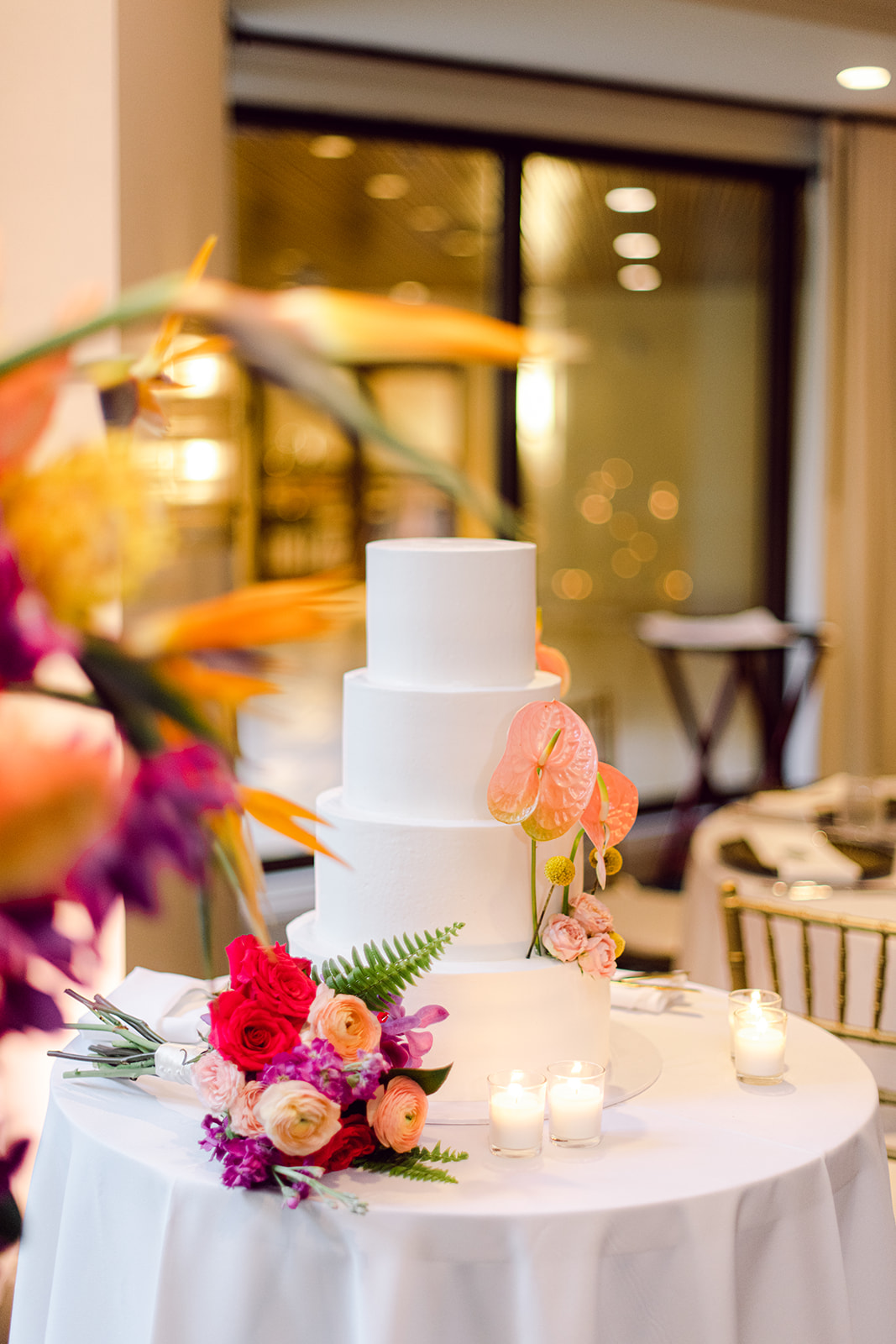 Photo of wedding cake with candles and flowers for reception at Mayfair House Hotel & Garden in Miami on wedding day.