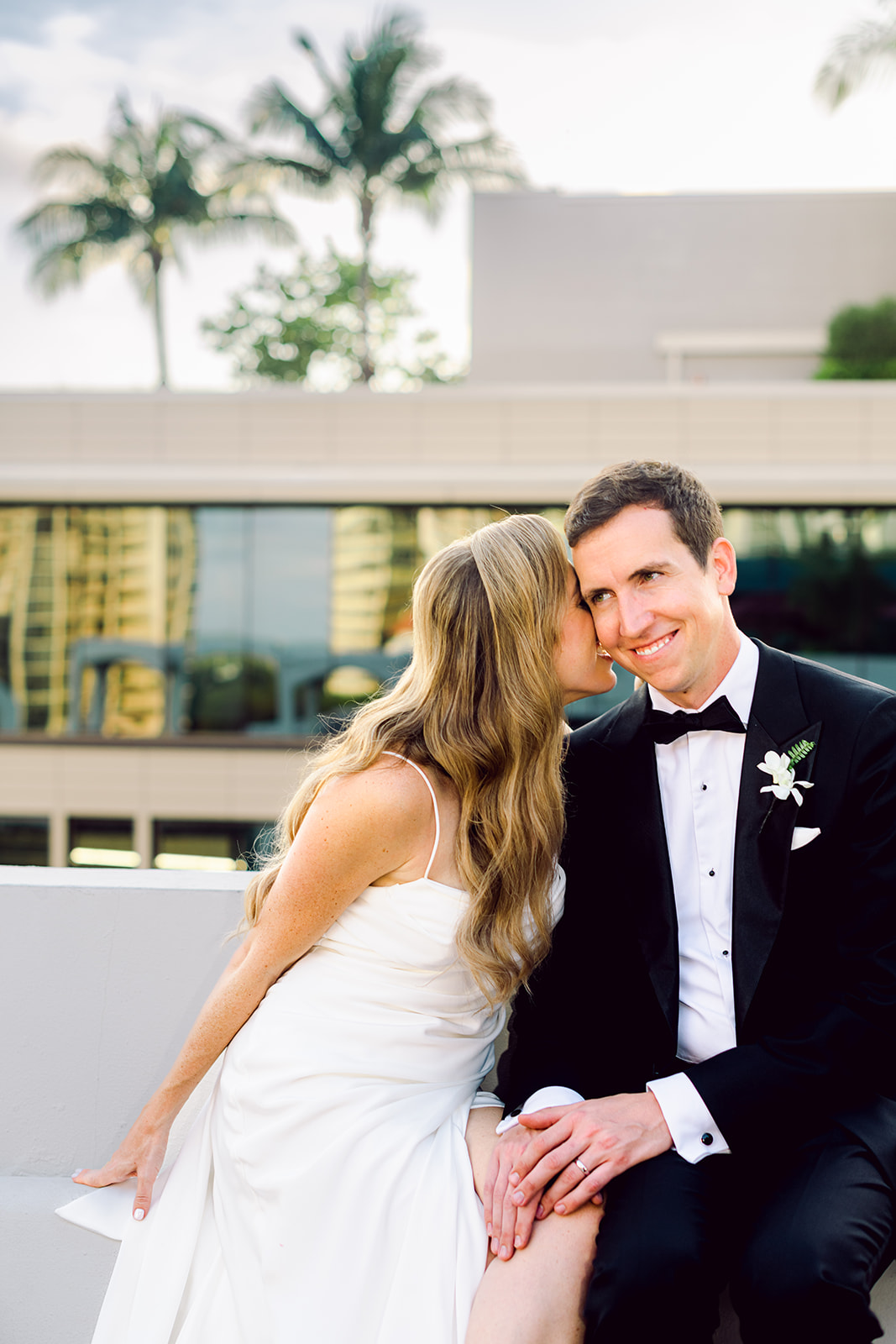 Couples golden hour portrait session bride whispers to groom at Mayfair House Hotel & Garden in Miami on wedding day.