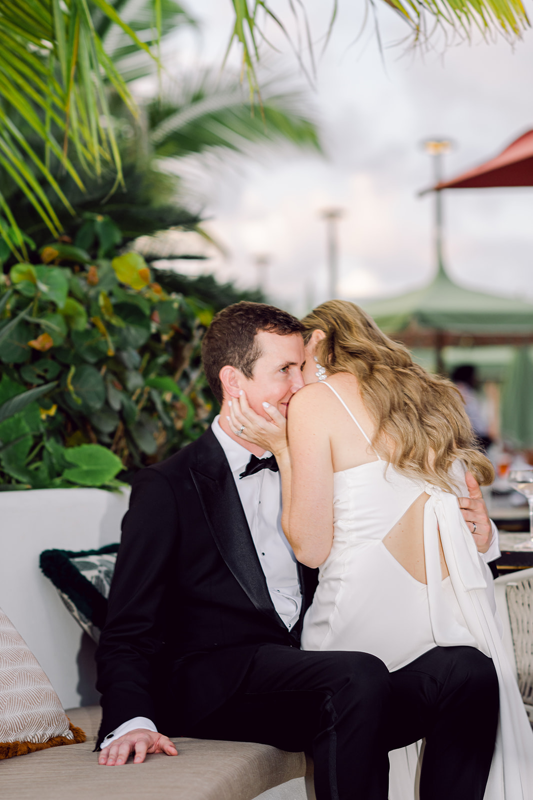 Bride on grooms lap kissing him on rooftop of Mayfair House Hotel & Garden in Miami on wedding day.