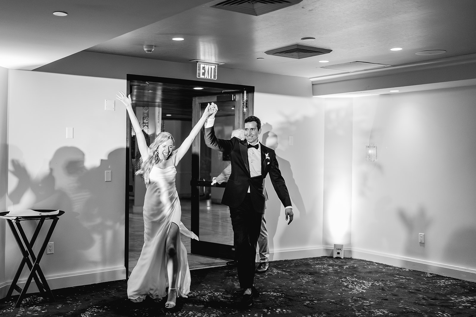 Black and white bride and groom enthusiastic enter reception hall at Mayfair House Hotel & Garden, Miami on wedding day.