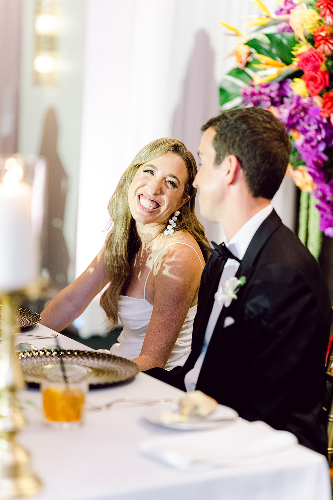 Bride smiles at groom during speech and toast at reception hall of Mayfair House Hotel & Garden, Miami on wedding day.