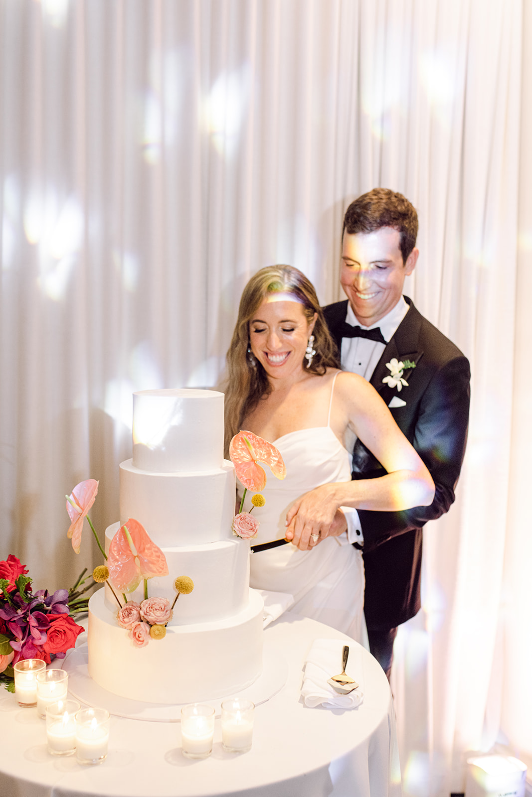 Color photo of bride and groom cutting cake in reception hall of Mayfair House Hotel & Garden, Miami on wedding day.