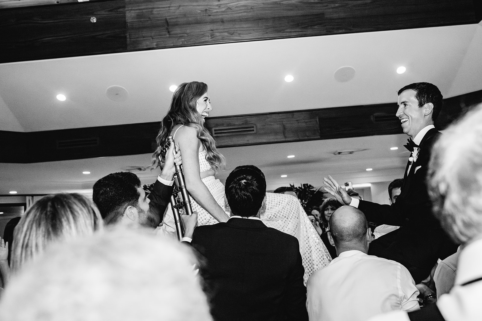 Black and white bride and groom during hora chair dance at reception Mayfair House Hotel & Garden, Miami on wedding day.