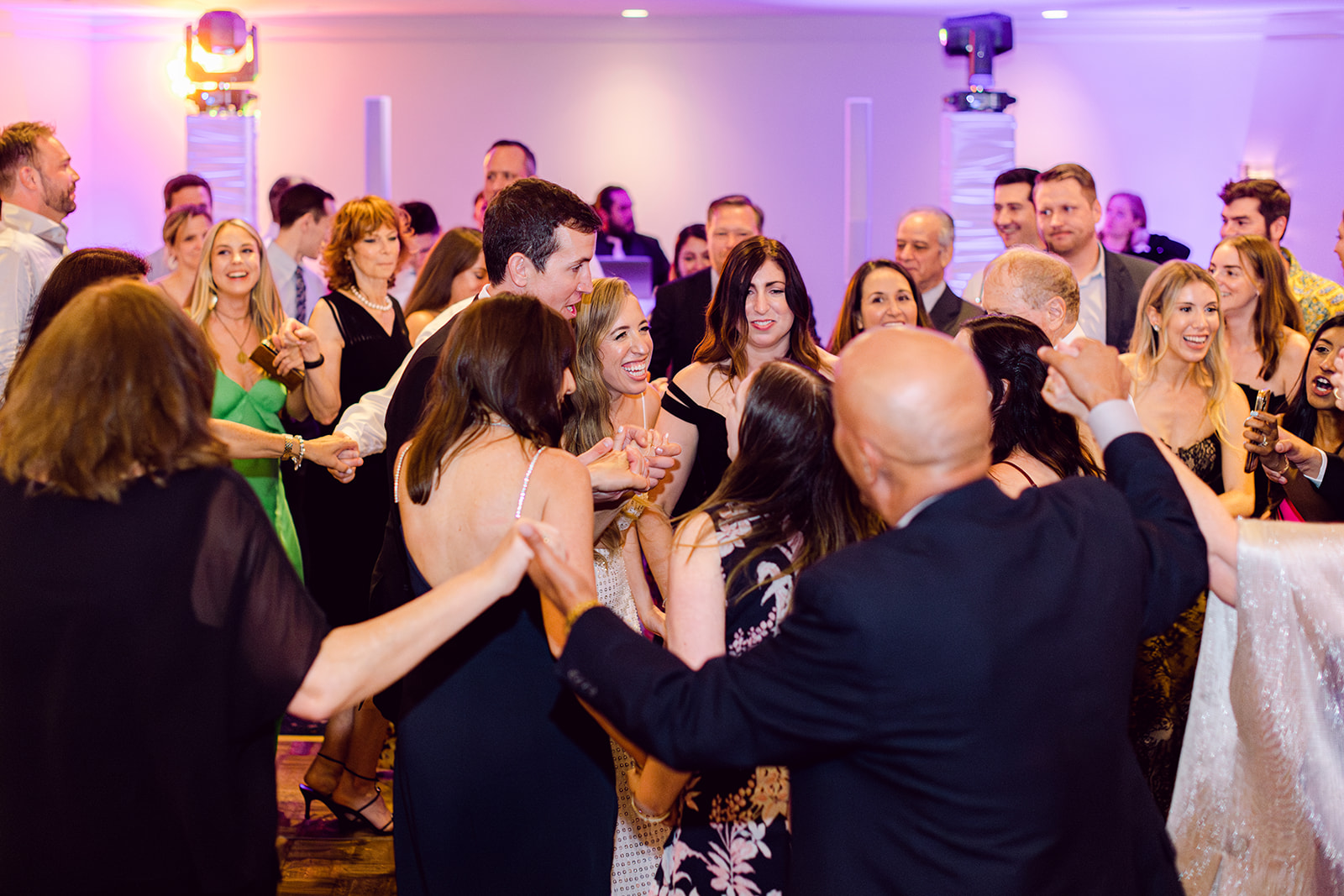 Candid of bride, groom and guests dancing hora at reception of Mayfair House Hotel & Garden, Miami on wedding day.