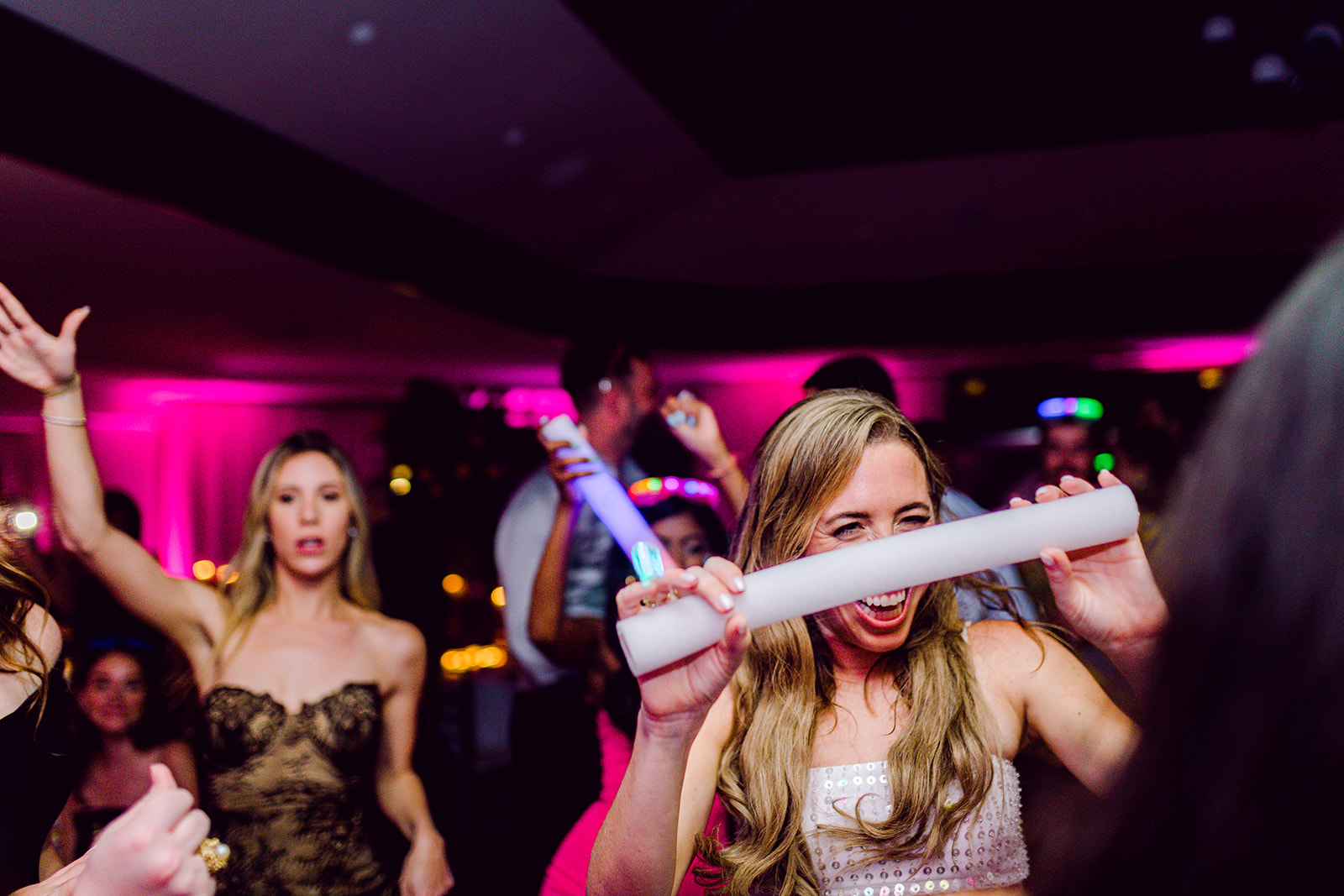 Bride dances with glow sticks on dance floor at wedding reception of Mayfair House Hotel & Garden, Miami.