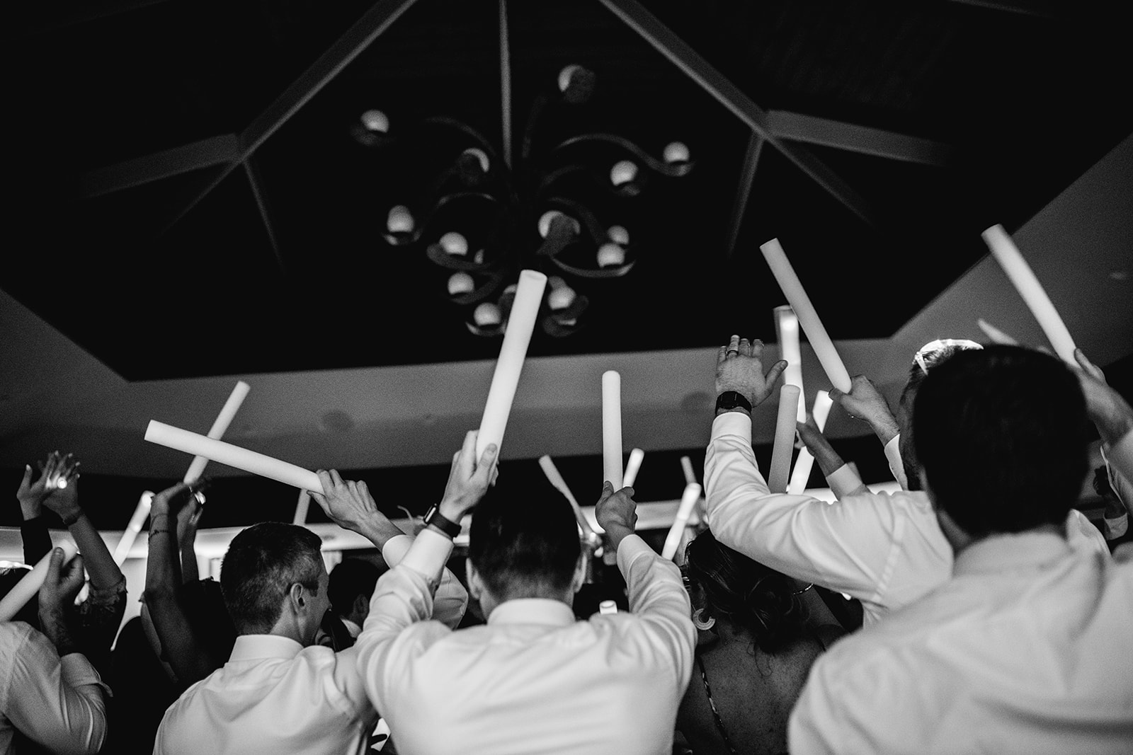 Black and white of guests with glow sticks on dance floor at wedding reception of Mayfair House Hotel & Garden, Miami.