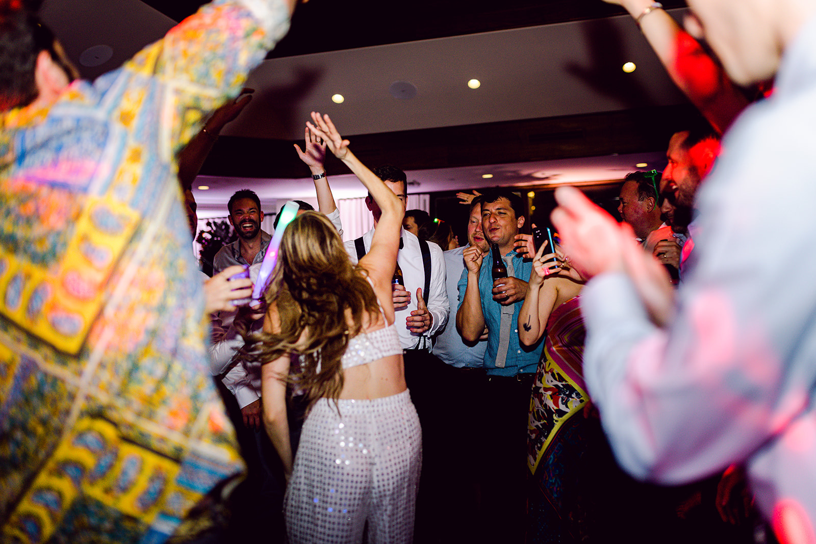 Bride and groom rave dancing together and wild crowd at wedding reception of Mayfair House Hotel & Garden, Miami.