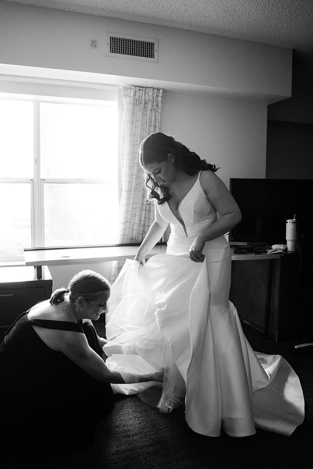 The bride is getting ready putting on her wedding dress with the mother of the bride in Orange County California