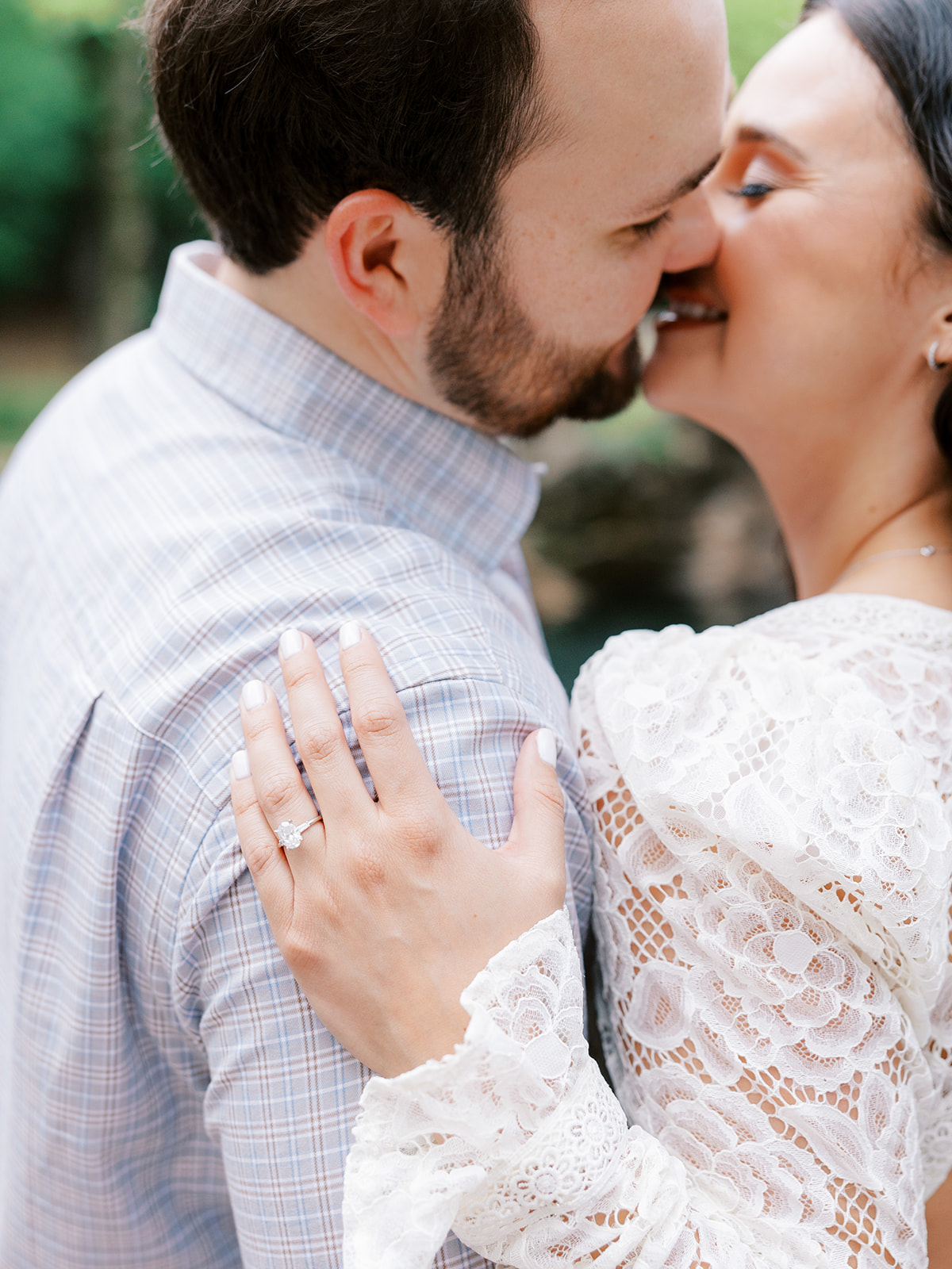 Closeup picture of couple leaning in for a kiss with focus on ring