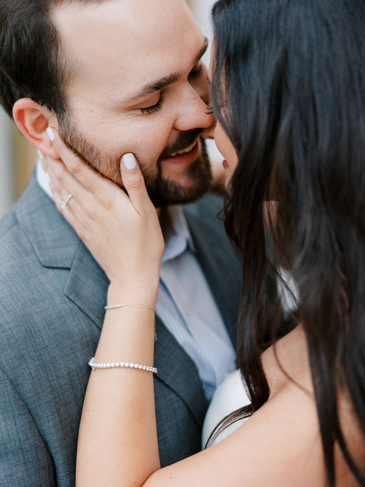 Fiance has hand on jaw as they lean in for a kiss