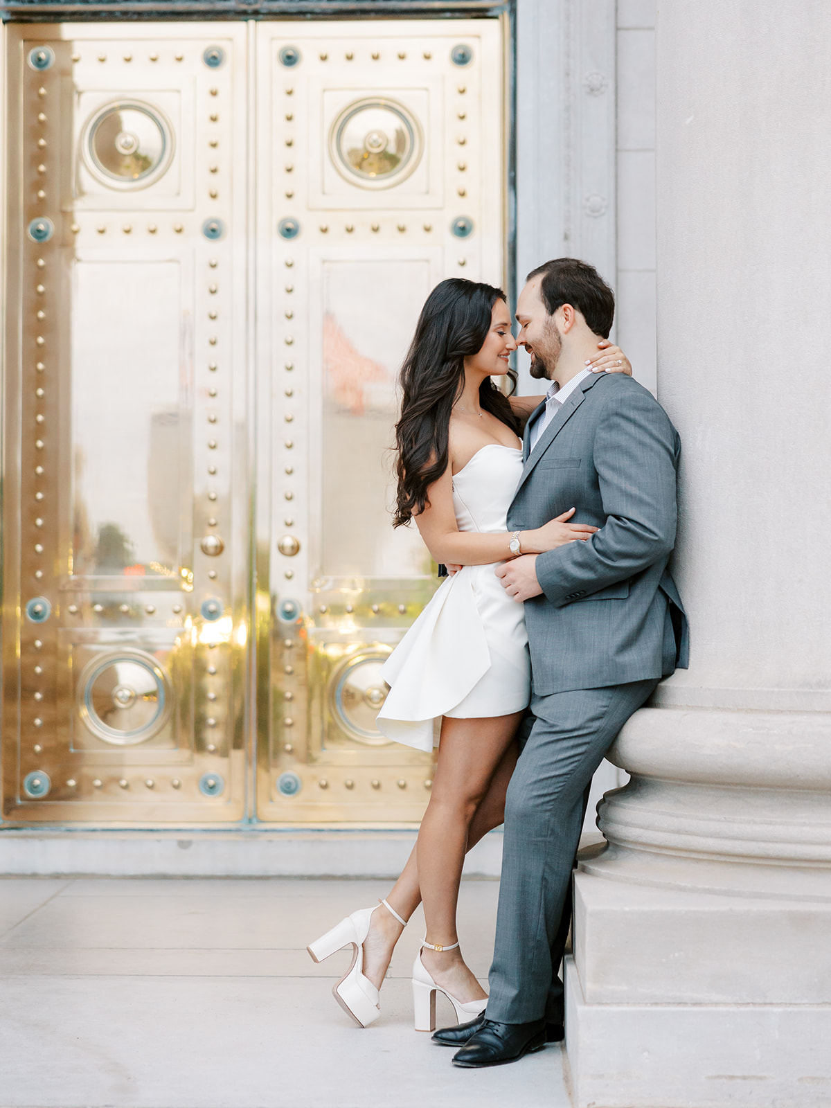Couple leaning close to each other in front of gold doors