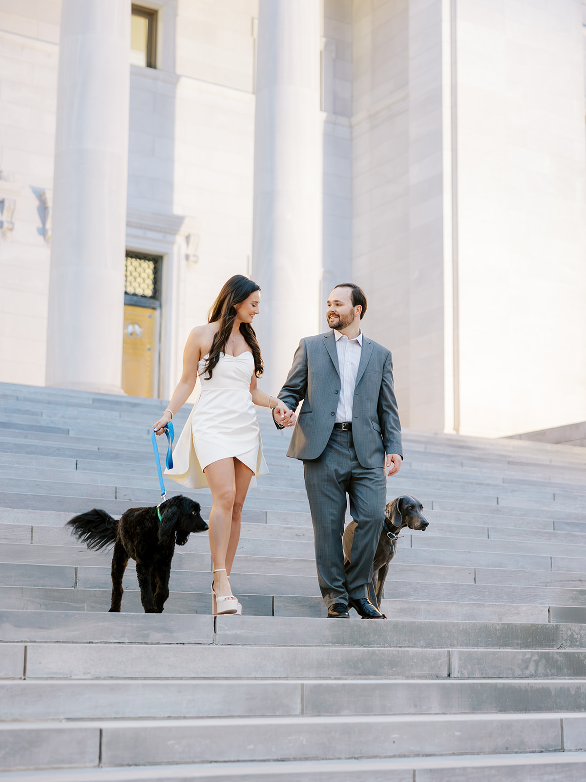 Couple with their two dogs walk down the steps of the Arkansas State Capitol