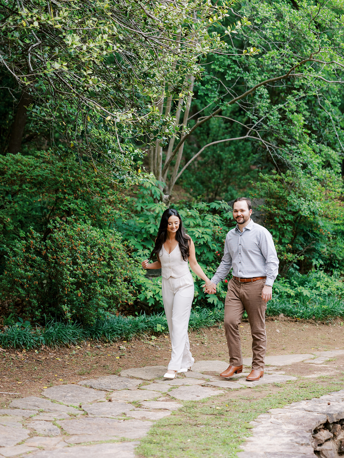 Couple walks together holding hands for engagement photos at Old Mill in Little Rock