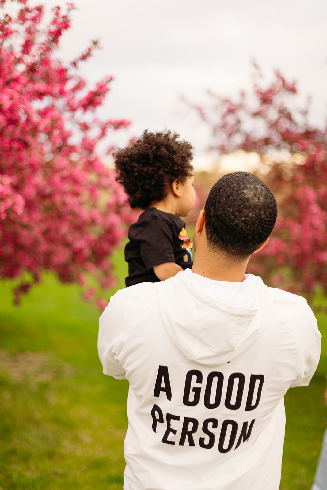 Be A Good Person brand sweatshirt in Denver Colorado with cherry blossom trees for family photos