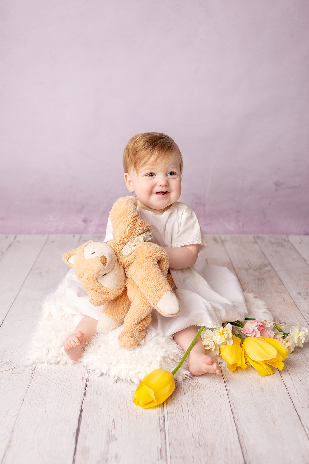 Milestone session for a first birthday of a little girl in all white dress with yellow tulips