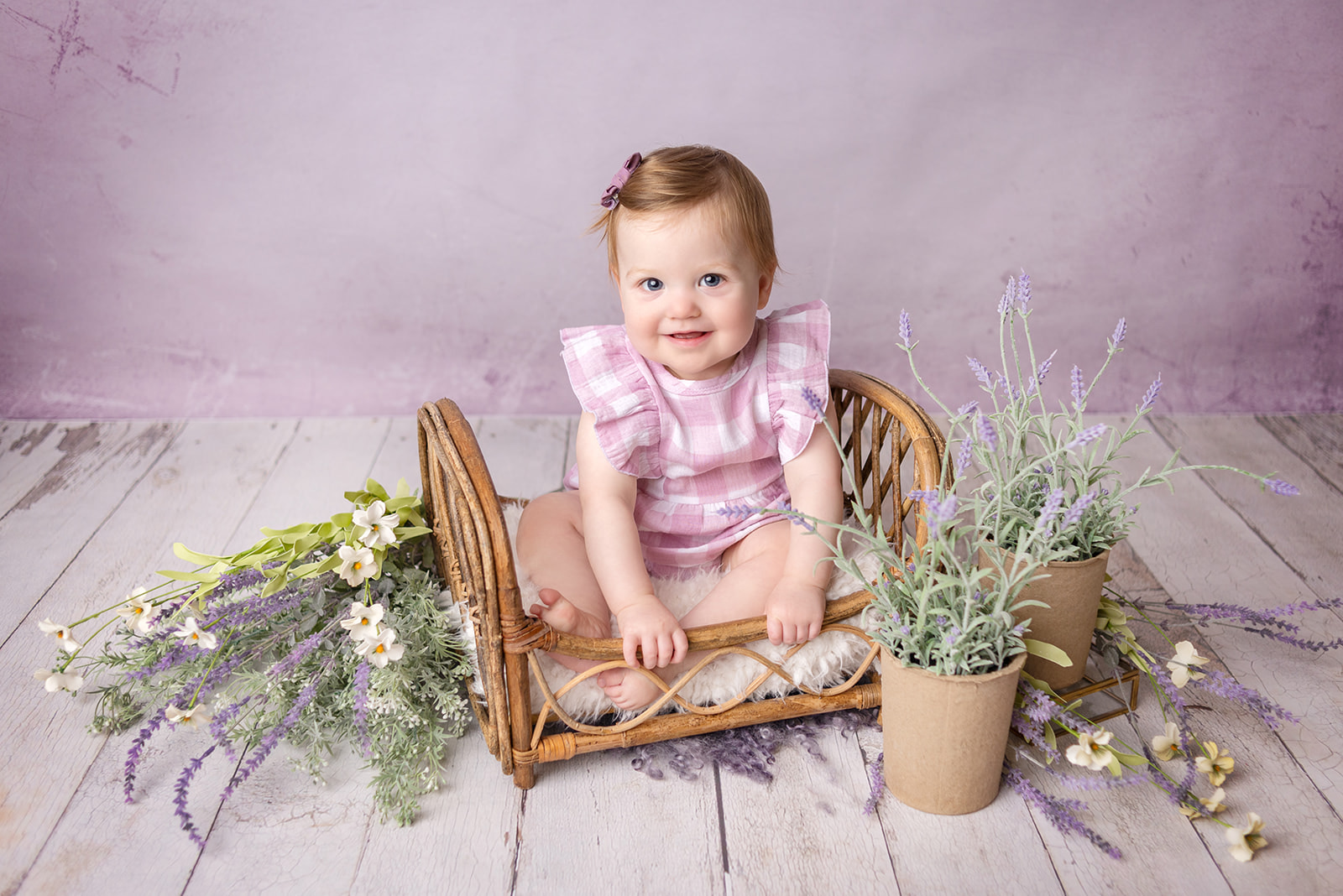 Smiling one year old girl in all purple at a photography studio located in Carthage, Missouri