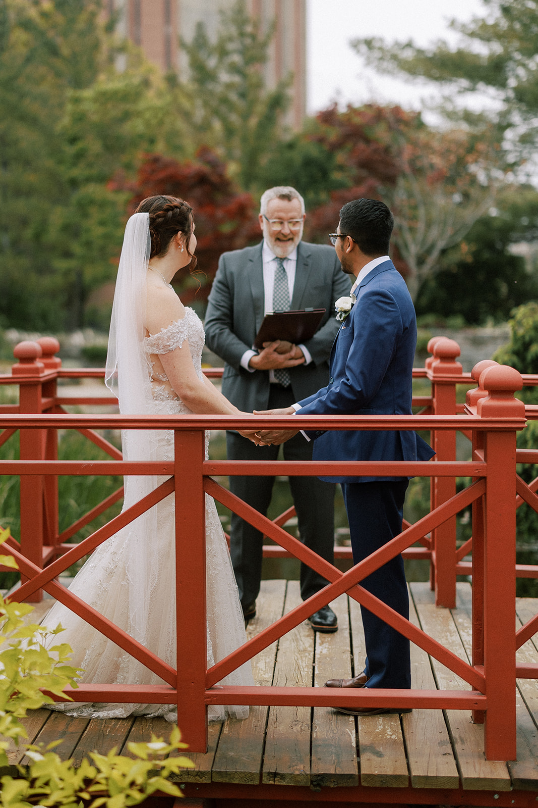 bride and groom stand on a bridge at the allen centennial gardens in madison wisconsin on their intimate wedding day