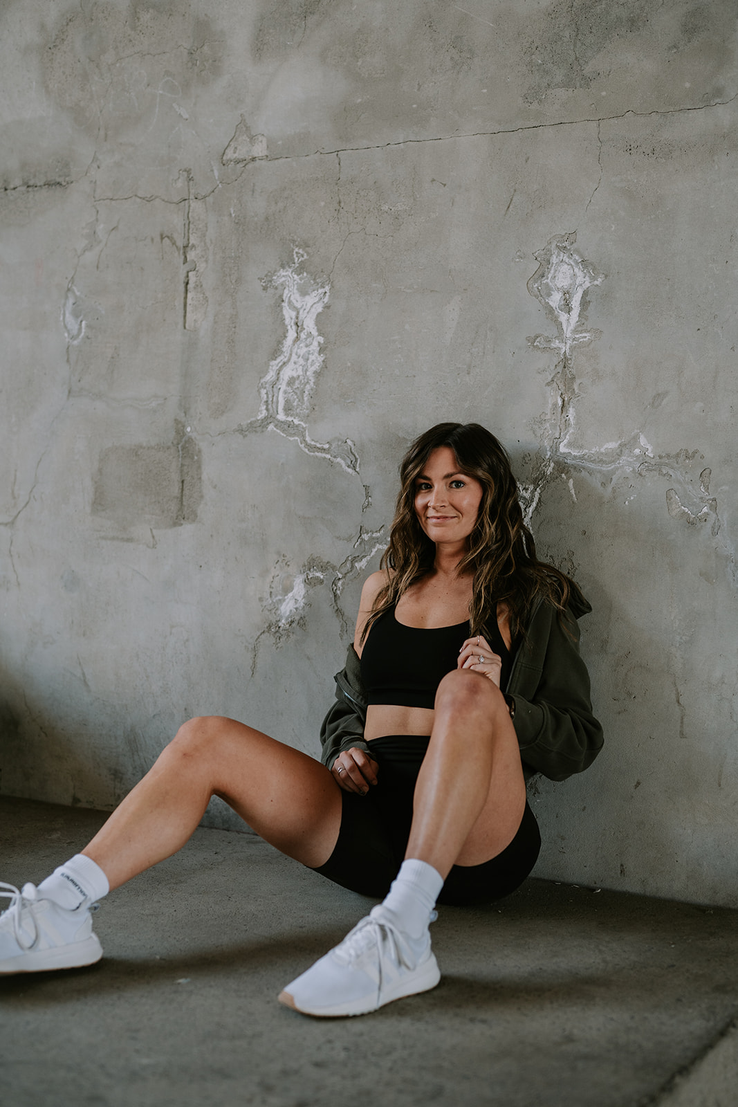 athletic woman sitting against cement wall