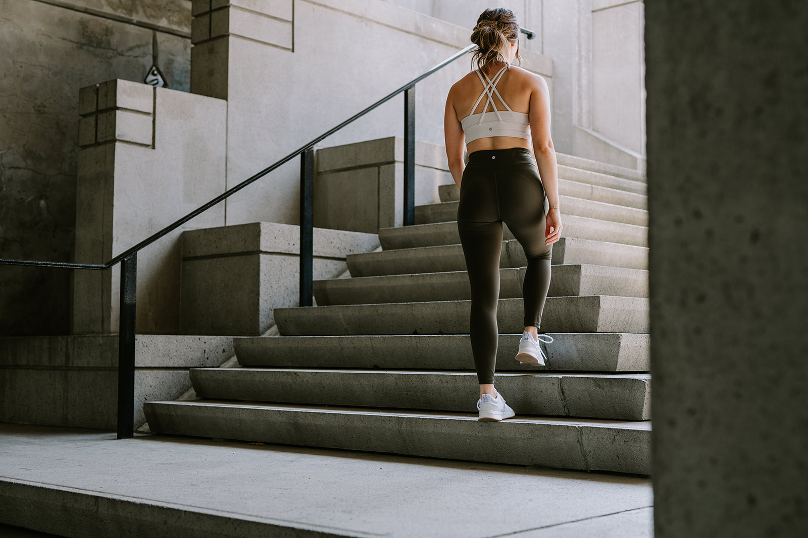 athletic woman climbing concrete staircase