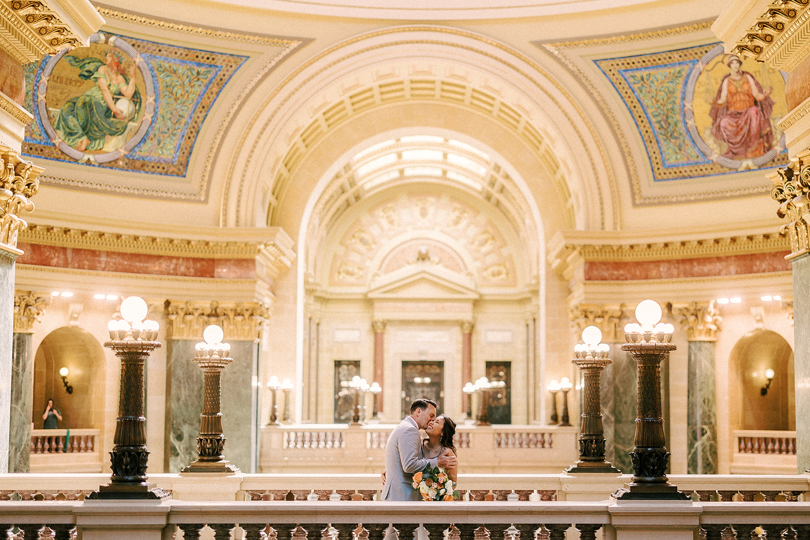 bride and groom kiss in the wisconsin state capitol buiding on their wedding day