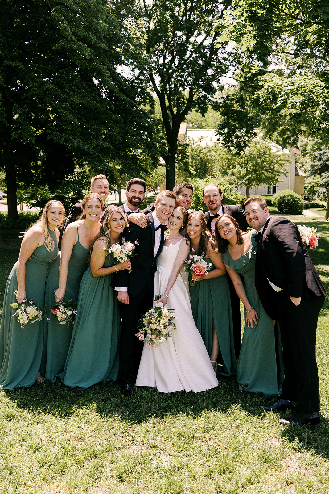 bride and groom pose for a group photo with their wedding party on their wedding day in madison wisconsin