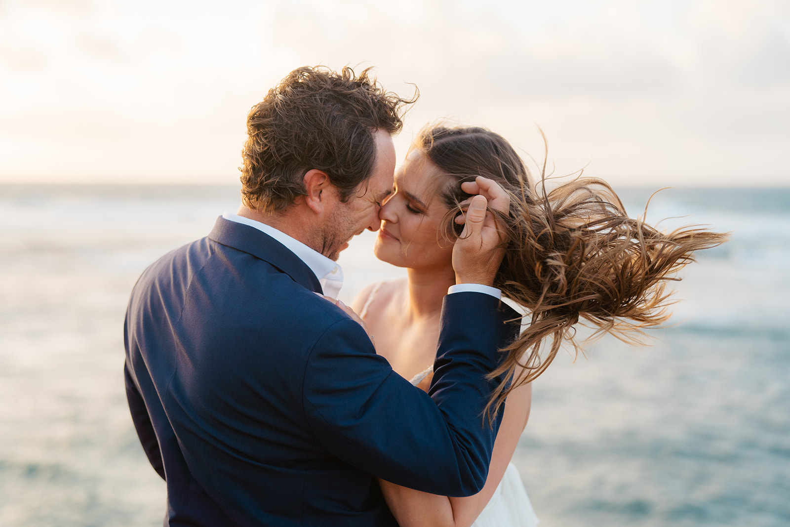 A couple who eloped on Kauai embrace on cliffs.