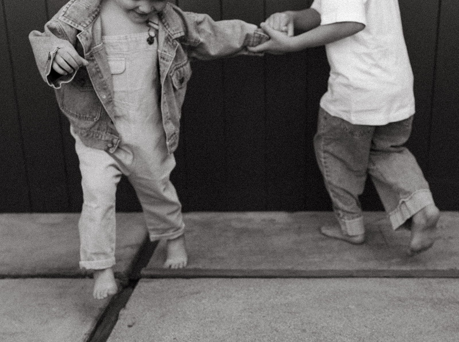 Black and white photo of brothers playing with each other in backyard