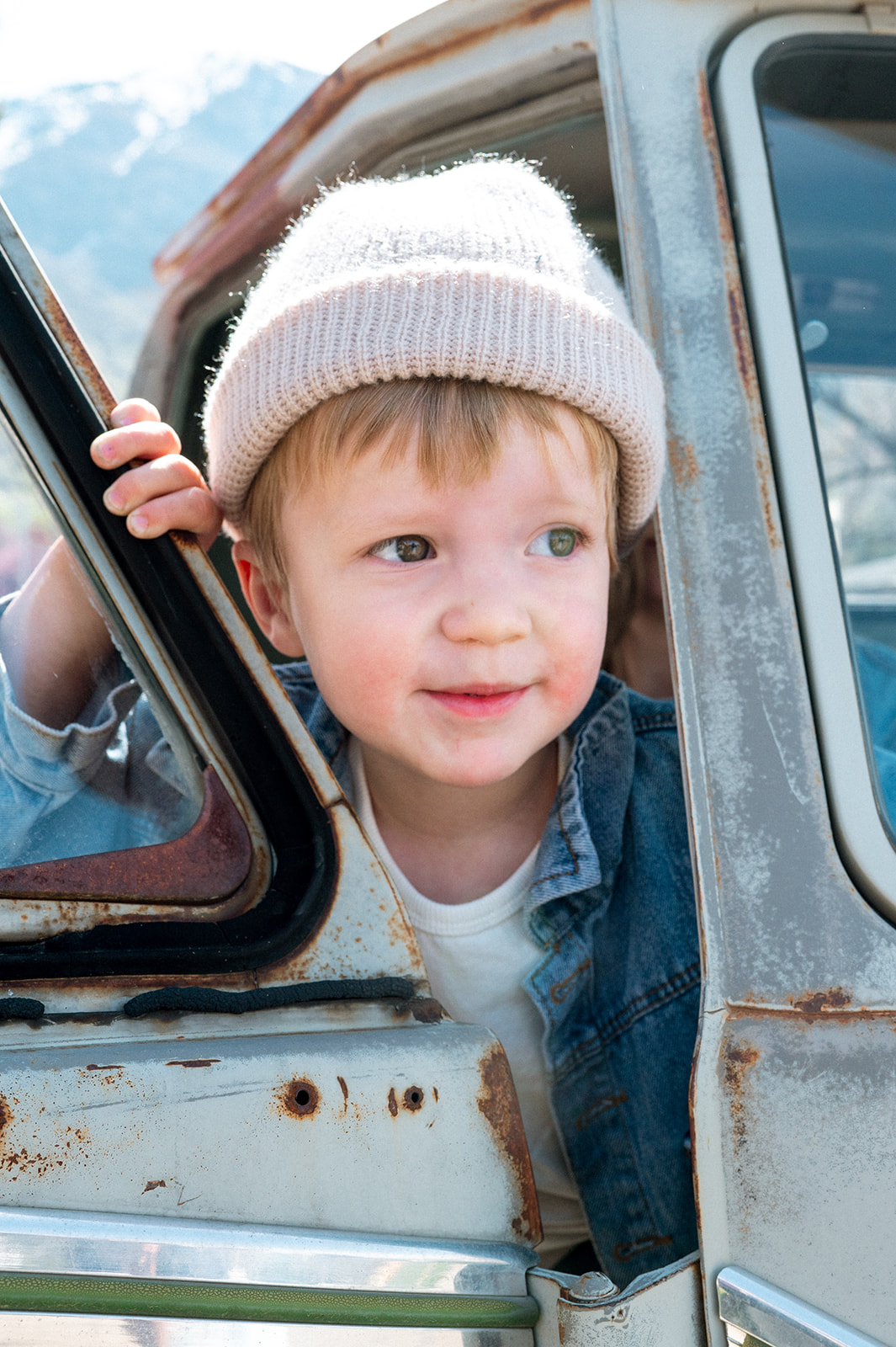 little boy wearing beanie peers out of truck in provo utah