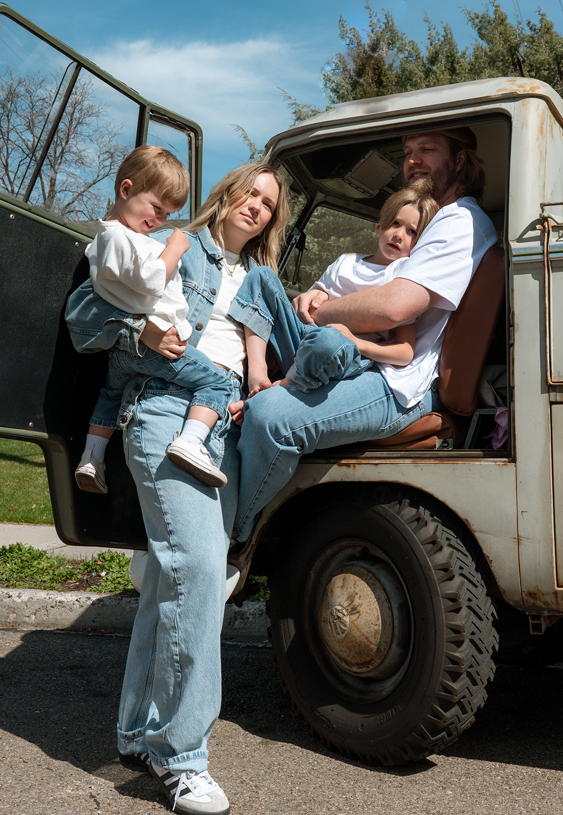 portrait of family of four sitting together in vintage VW truck