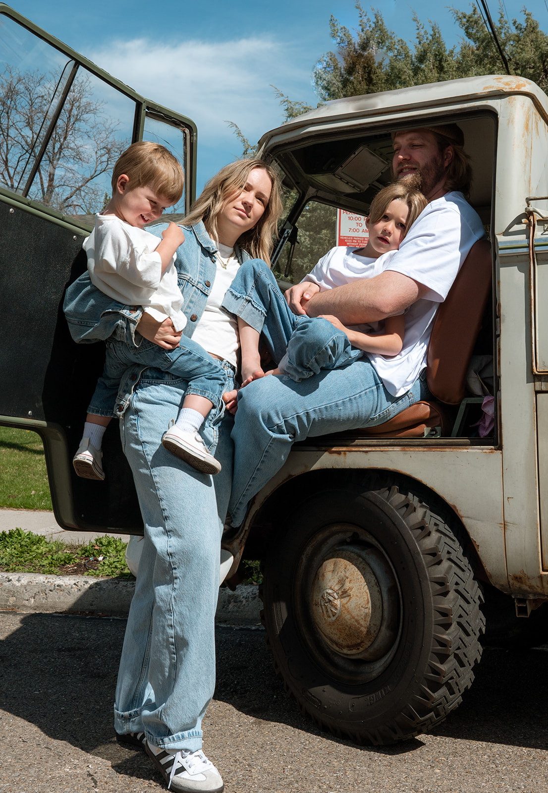 portrait of family of four sitting together in vintage VW truck