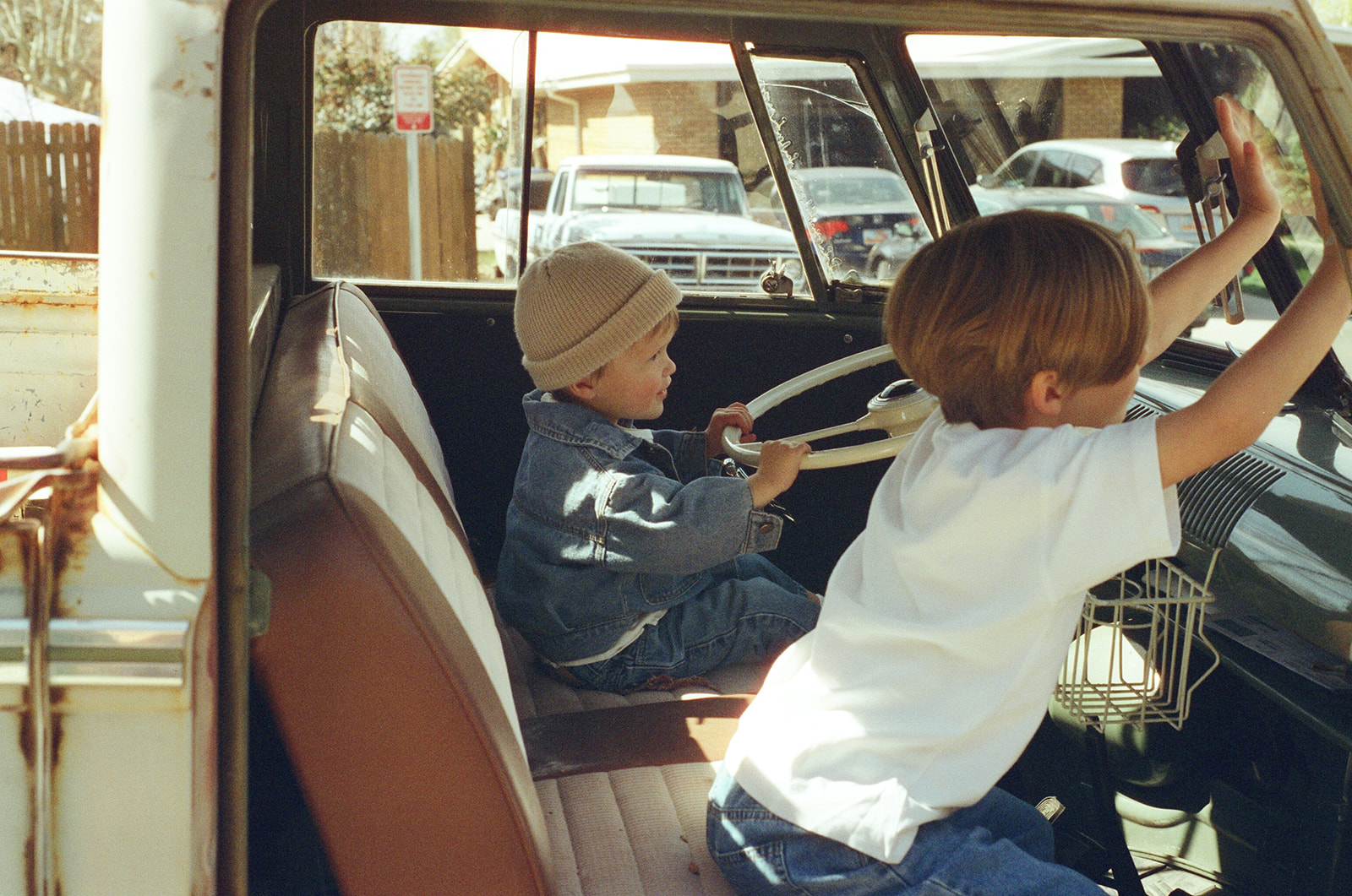 candid film photo of two brothers play in front seat of vintage VW truck
