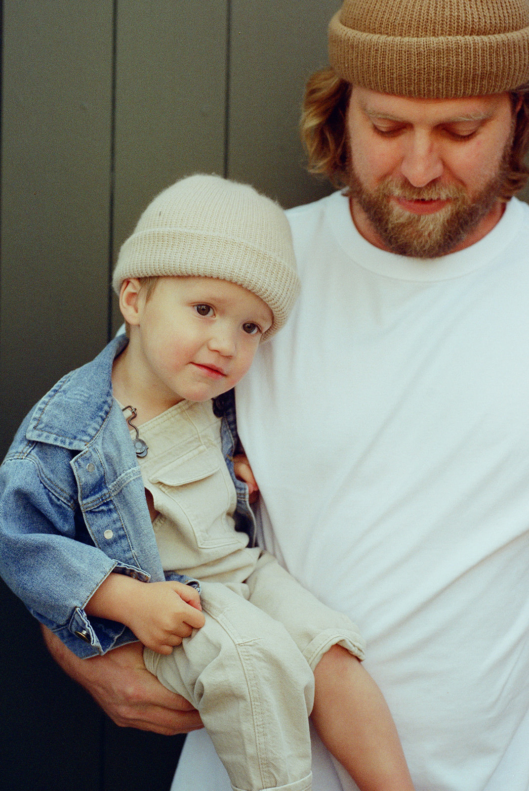 film portrait of dad holding son both wearing beanies