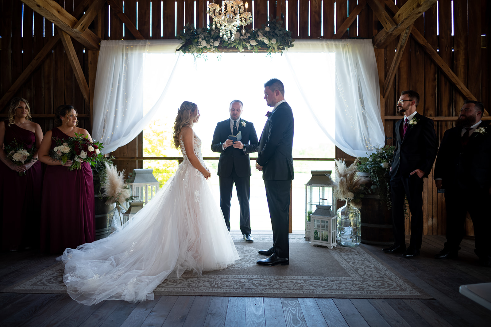 bride and groom saying vows in barn at glistening pond