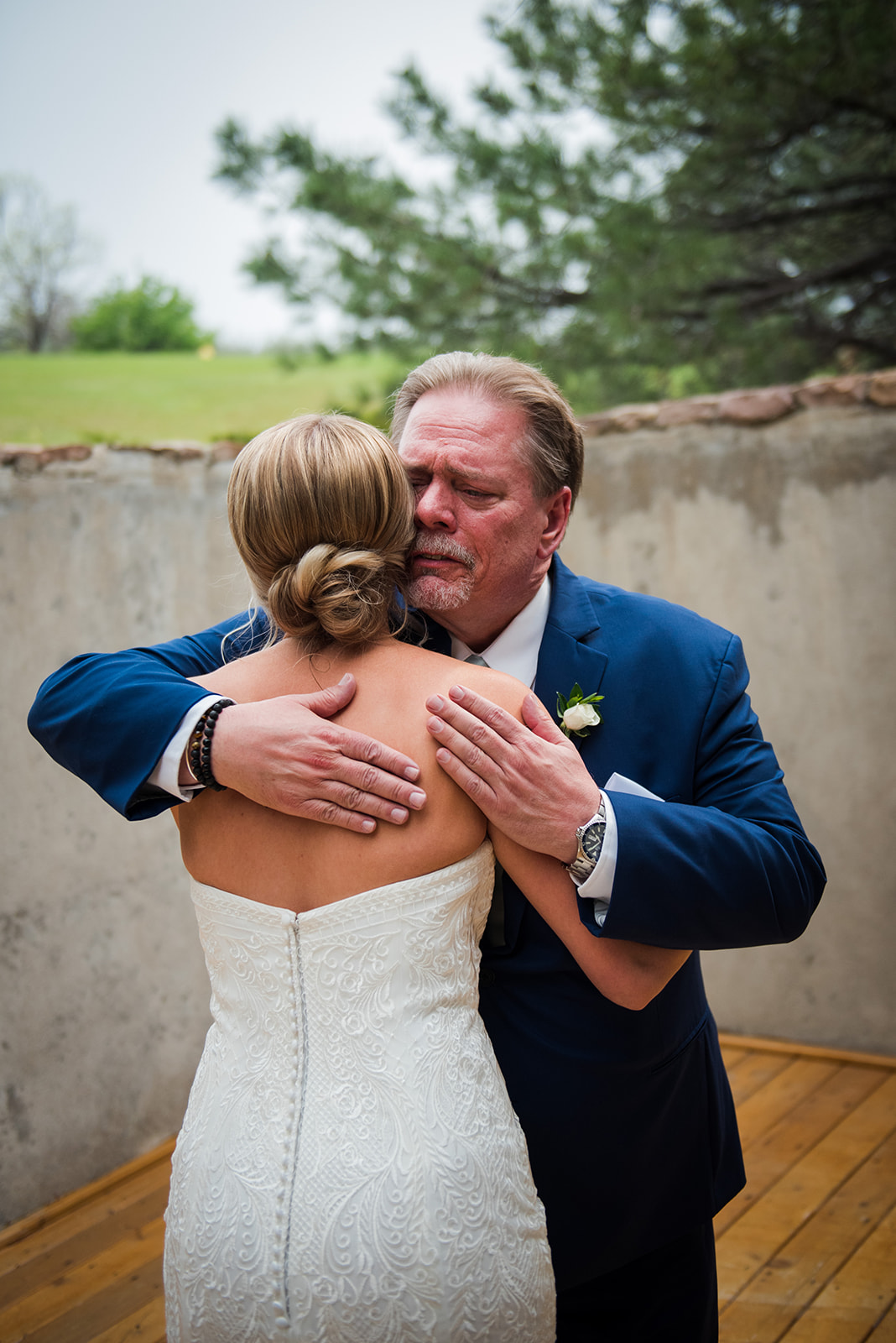 Bride's father hugs her emotionally after seeing her for the first time in her wedding dress.