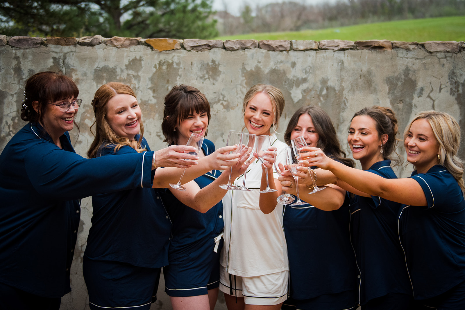 Bridesmaids and bride stand together toasting with glasses of champagne.