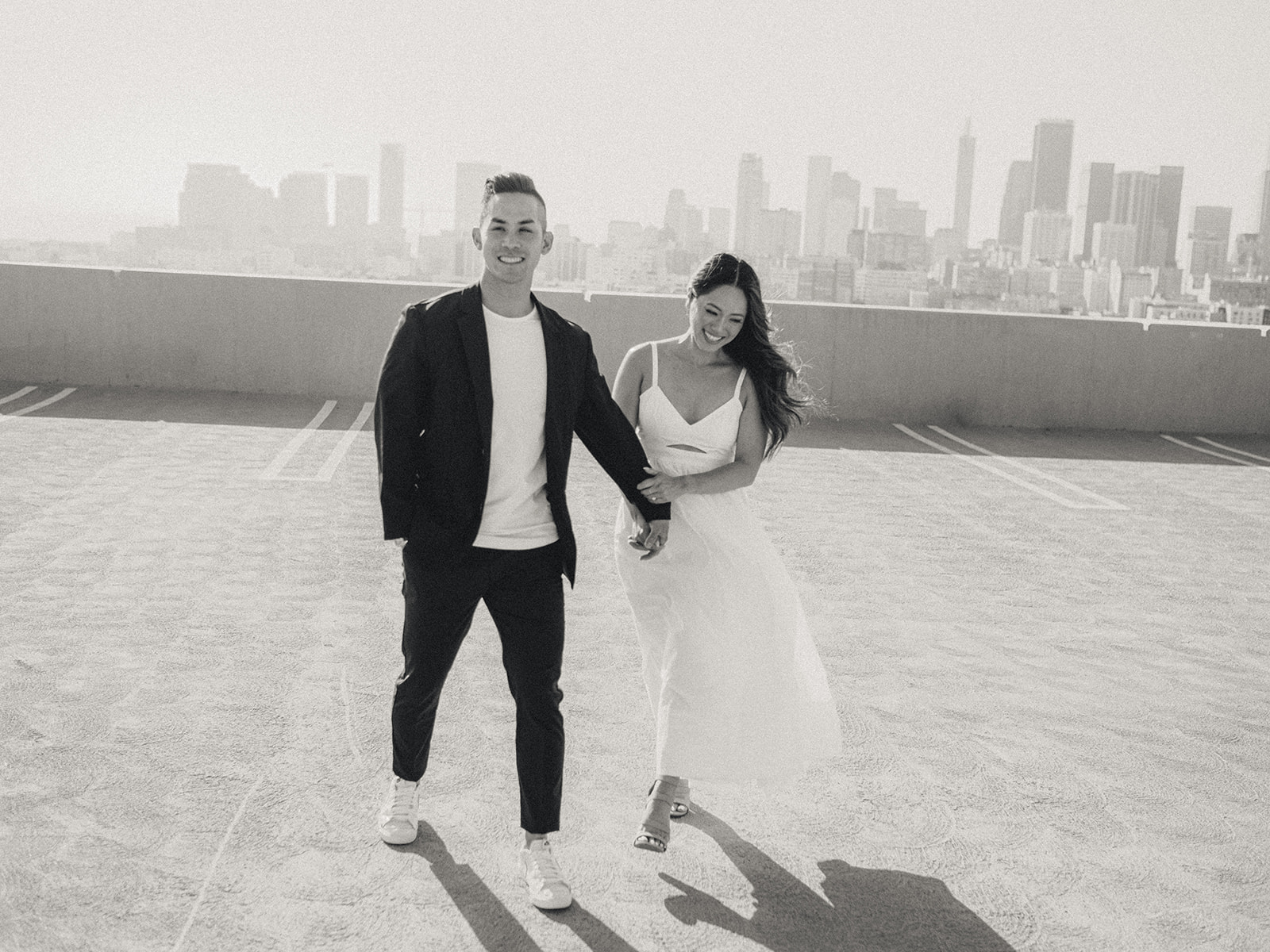A couple in love walks toward the camera on a roof top overlook Los Angeles. 