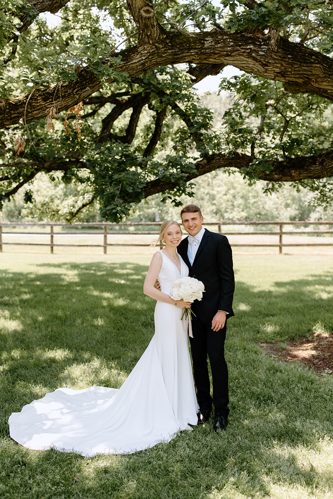 Bride and groom smile under a tree