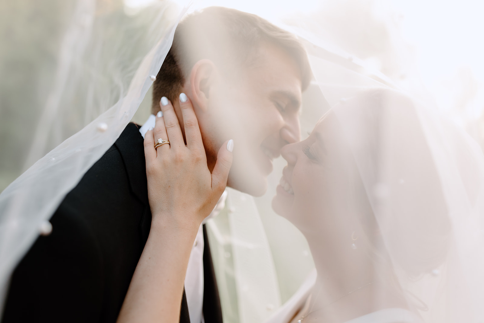 Bride and groom kiss underneath veil
