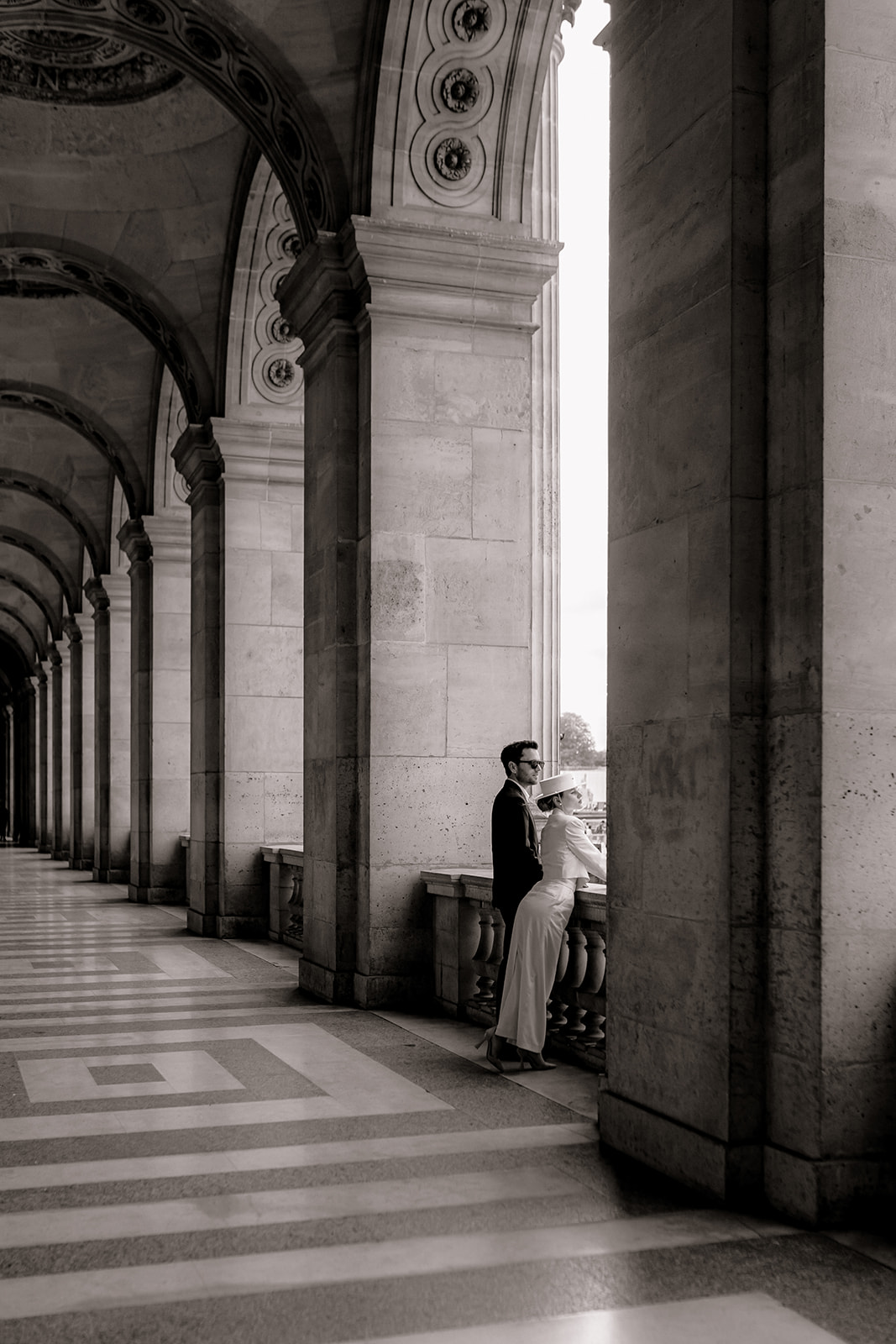 Sophisticated elegant french couple posing at the louvre in Paris in between the columns