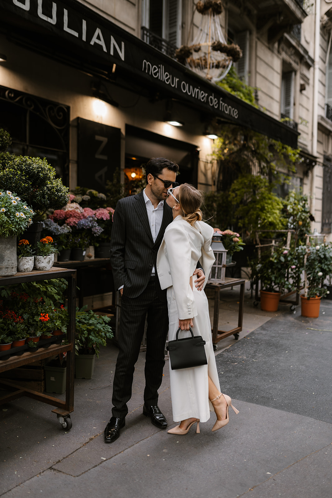 Sophisticated elegant french couple kissing in front of a flower shop