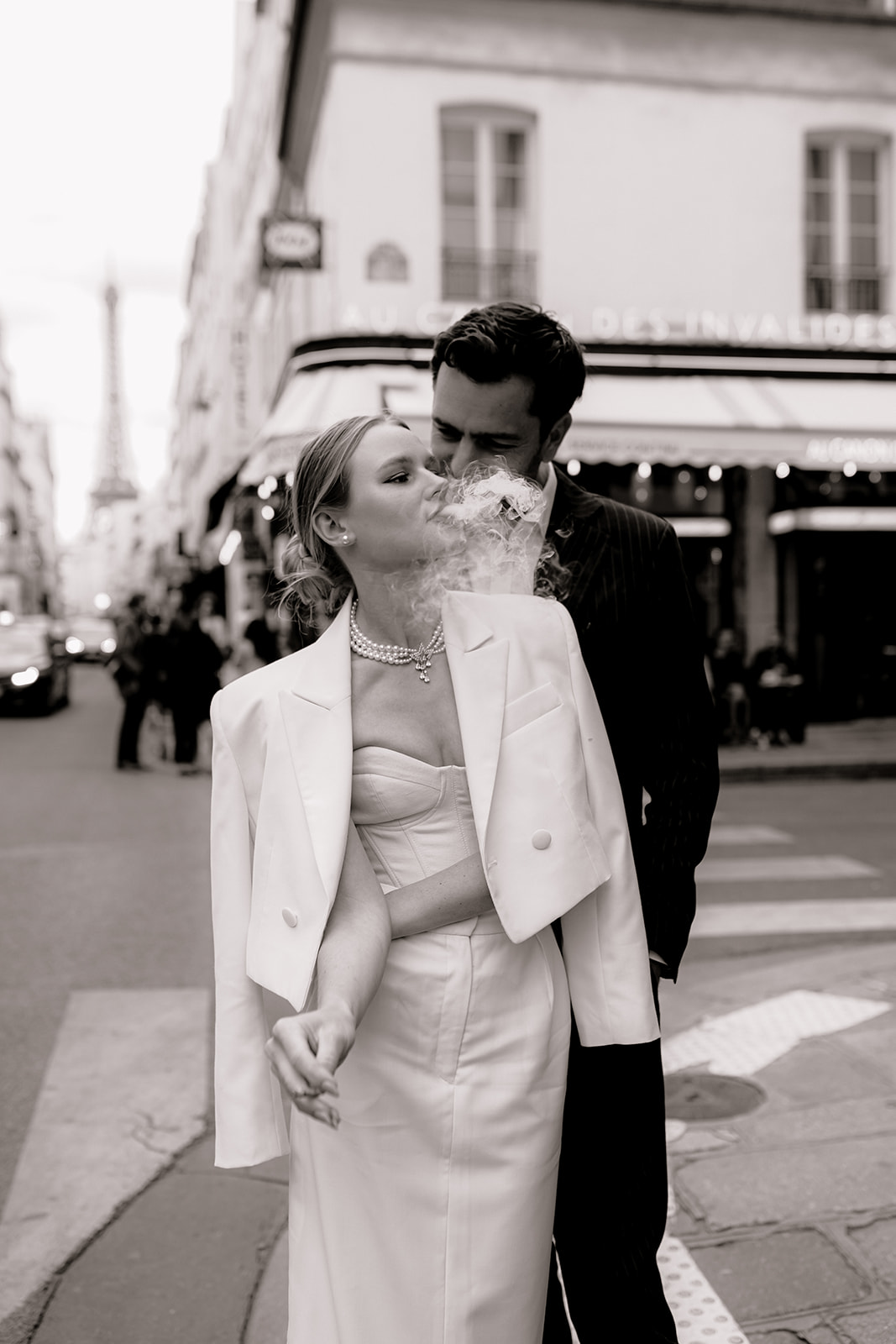 Sophisticated elegant french couple having a smoke in front of a french bistrot and the tour eiffel in the background