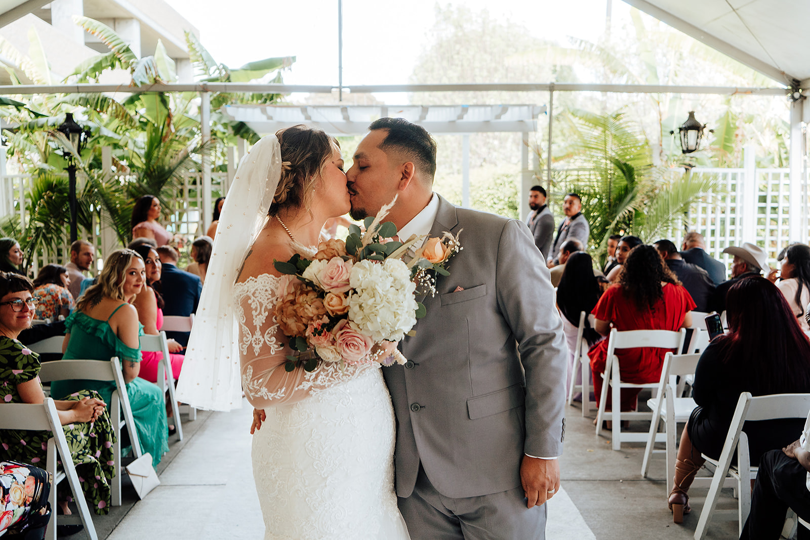 Bride and groom in Long Beach California kiss at the end of the aisle at The Grand 